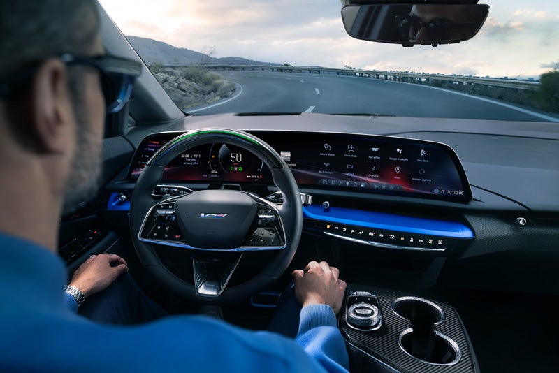 Front View of the 2026 OPTIQ-V Driving Through the Dusk Utilizing its Headlights | Cadillac of Tucson in Tucson AZ