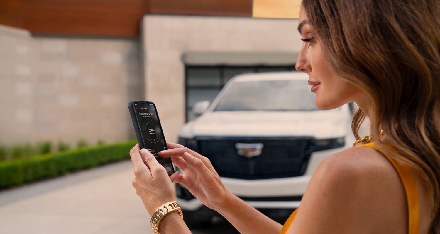 lady checking her mobile with a Cadillac vehicle background | Cadillac of Tucson in Tucson AZ